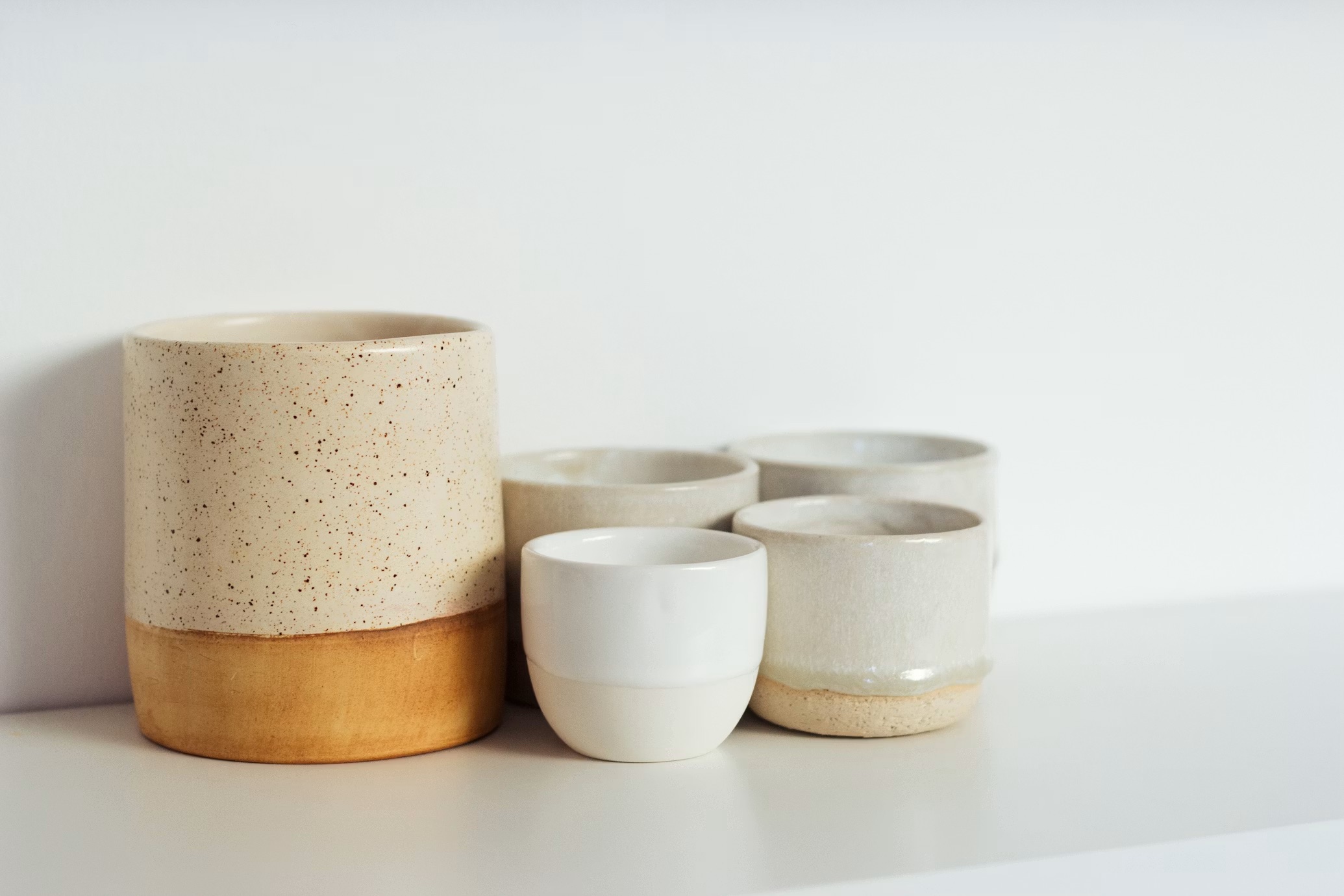Tasses et pots en grès de l'atelier Ternalie, alignés sur une étagère
