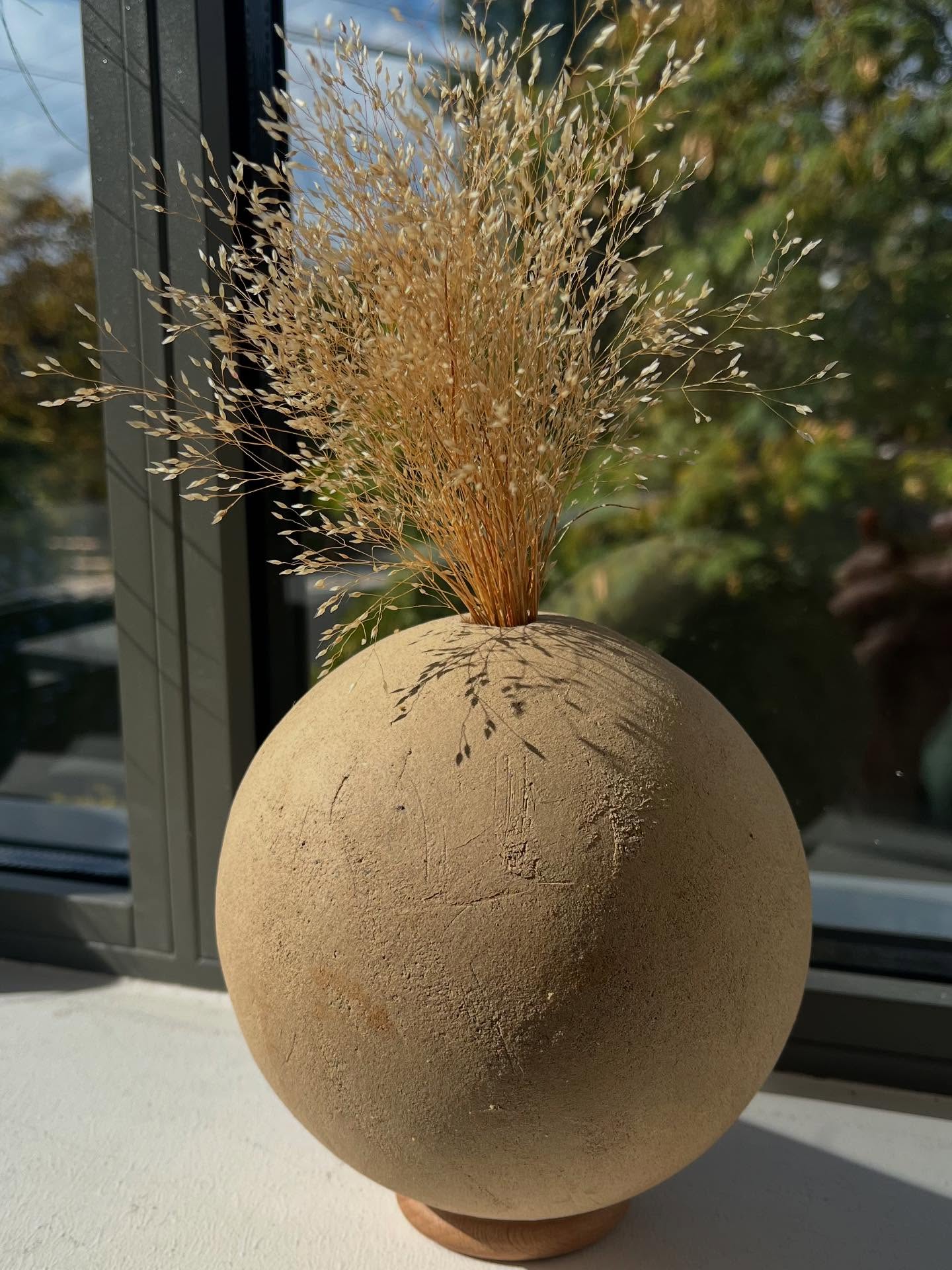 Vase boule en grès chamotté brut avec graminée